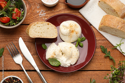 Delicious burrata cheese with arugula and fresh bread on wooden table, flat lay