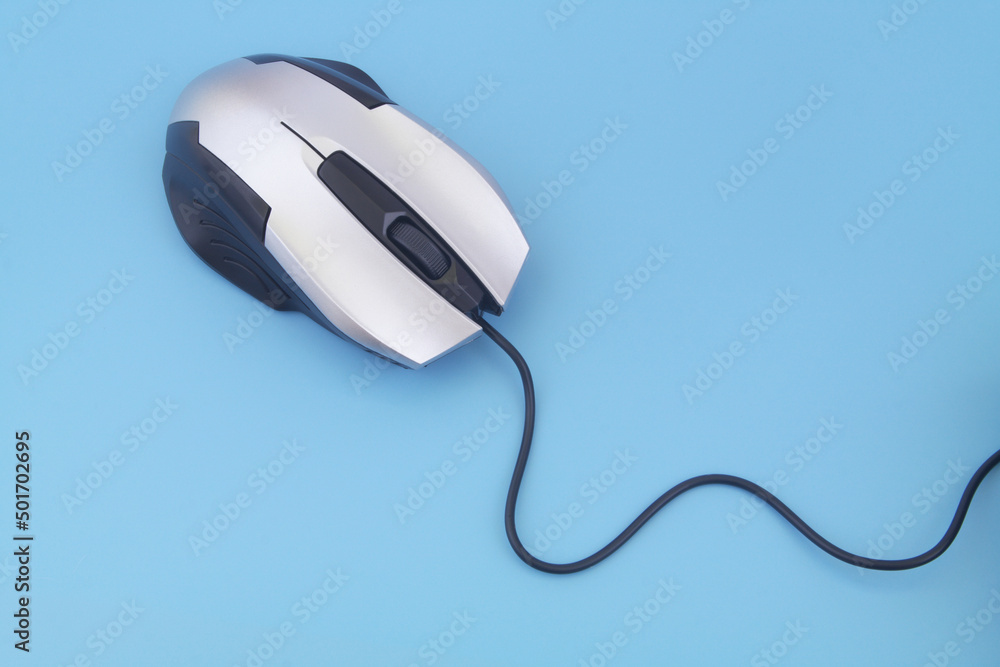 Silver computer mouse with cord on blue background Silver computer mouse with cord on blue background