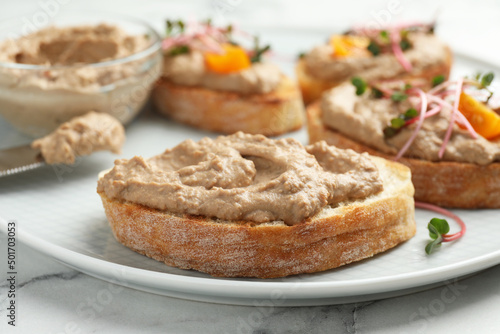 Slices of bread with delicious pate on white marble table, closeup