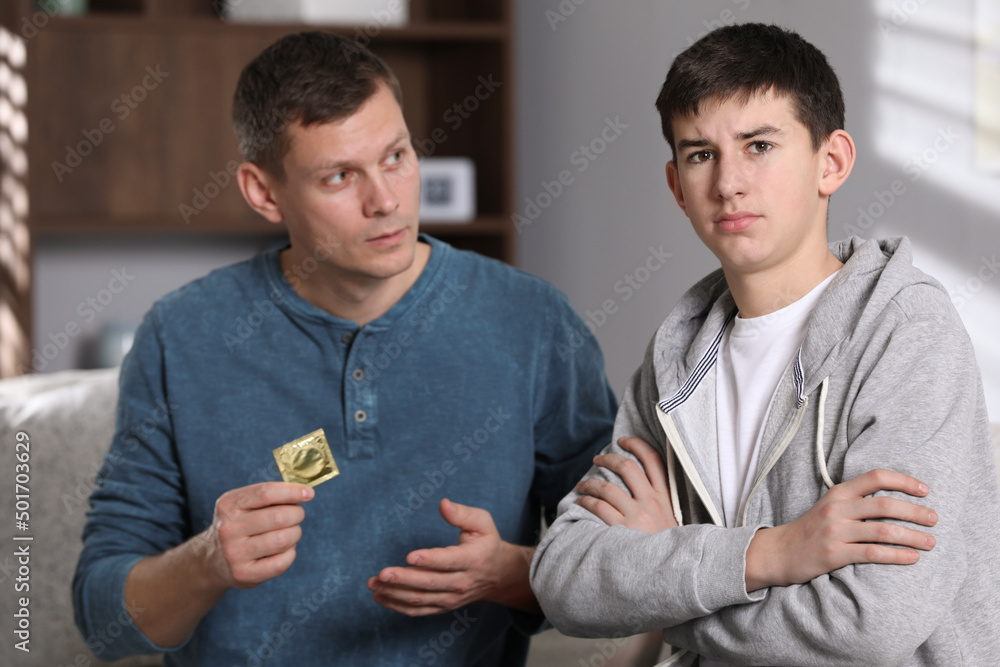 Father talking with his teenage son about contraception at home. Sex