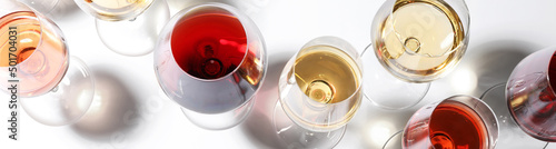 Glasses with different wines on white background, top view. Banner design