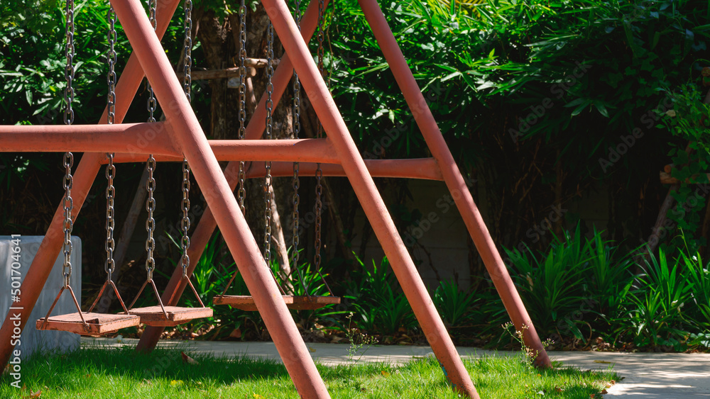 The old metal swing with many green plant in gardening area at public park, side view with copy space The old metal swing with many green plant in gardening area at public park, side view with copy space