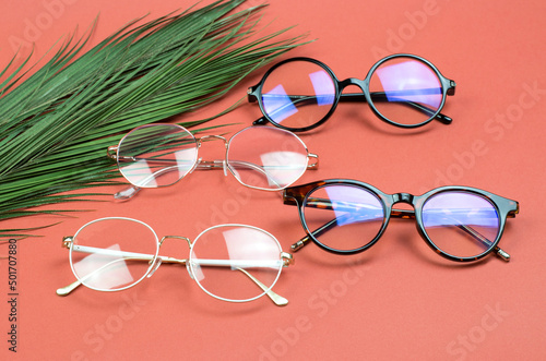 Stylish women's glasses on a colored background with palm leaves