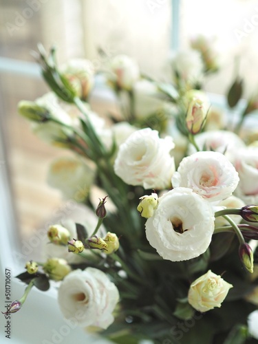 Beautiful spring delicate bouquet of white flowers of lisianthus, eustoma on the window close-up. Mother's day card. Wedding concept. Floristry, floral studio