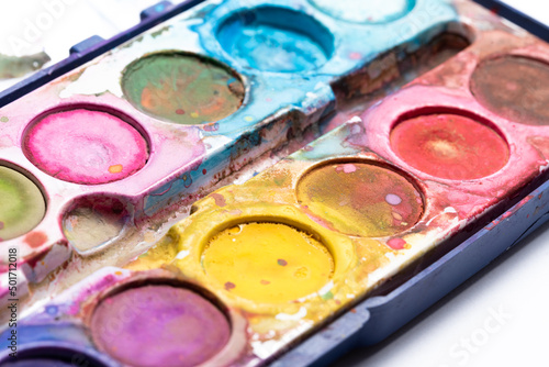Blurry watercolor paints in close-up. Dirty paint packaging. Accessories for art work for children.
