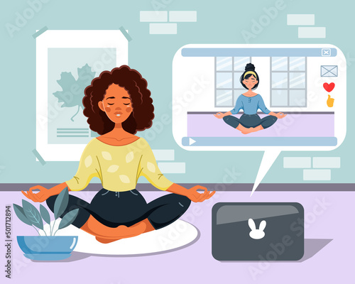 An African-American woman watches online classes on a laptop and does yoga