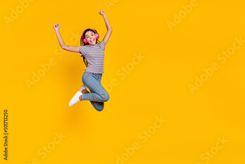 Full body photo of young excited girl have fun rejoice success fists hands melody sound isolated over yellow color background © deagreez