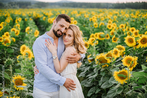 Couple walks in the sunflowers in a field on a summer day