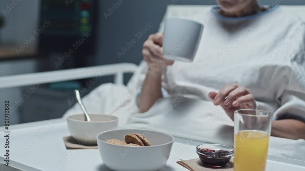 Midsection of cropped patient sitting in bed in hospital room, eating cookie with jam and drinking coffee Midsection of cropped patient sitting in bed in hospital room, eating cookie with jam and drinking coffee