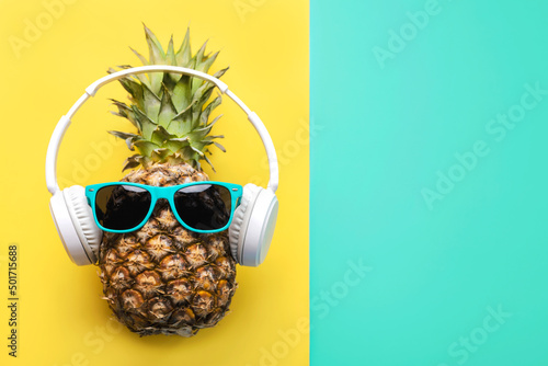 Summertime concept. Pineapple with blue sunglasses, headphones and space for text photo