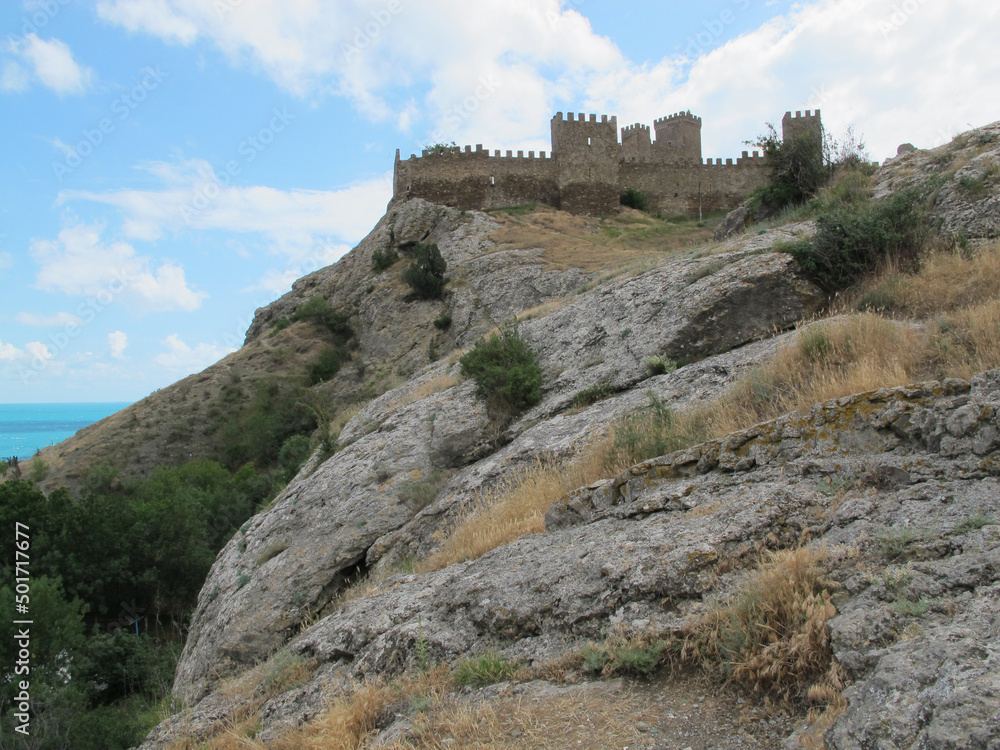 Panorama of the Ancient Genoese fortress, against the background of rocks, sea and blue sky with clouds, Sudak, Crimea