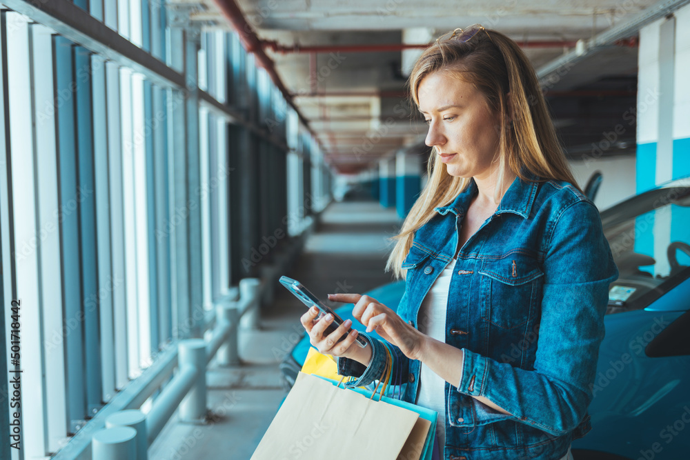 Photo of Businesswoman sending a message with a smartphone. A young proud businesswoman is talking on her mobile phone with a client and reading order. A young Caucasian woman standing nearby car Photo of Businesswoman sending a message with a smartphone. A young proud businesswoman is talking on her mobile phone with a client and reading order. A young Caucasian woman standing nearby car