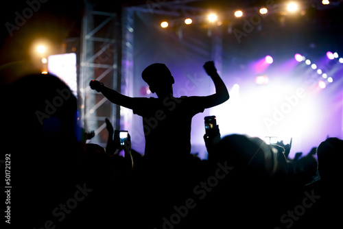 Viewers under the stage. The man with raised hands during summer festival rock concert.
