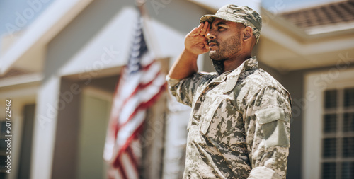 Patriotic young soldier saluting outdoors photo