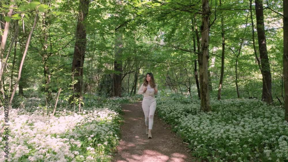 Girl walks in a flowery woods towards camera. Girl walks in a flowery woods towards camera.