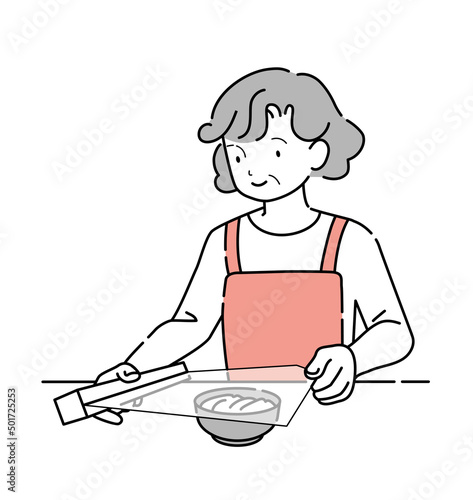食器に食品用ラップをかける年輩女性