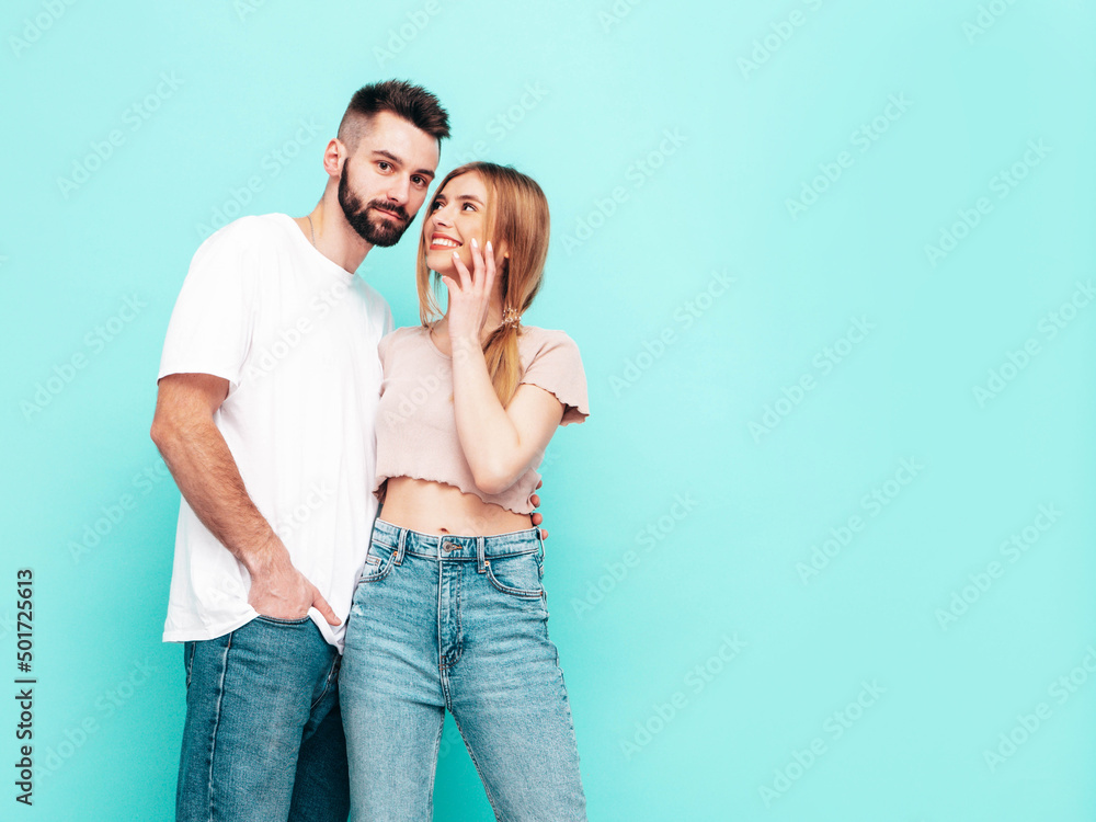 Naklejka premium Sexy smiling beautiful woman and her handsome boyfriend. Happy cheerful family having tender moments near blue wall in studio.Pure cheerful models hugging.Embracing each other. Cheerful and happy