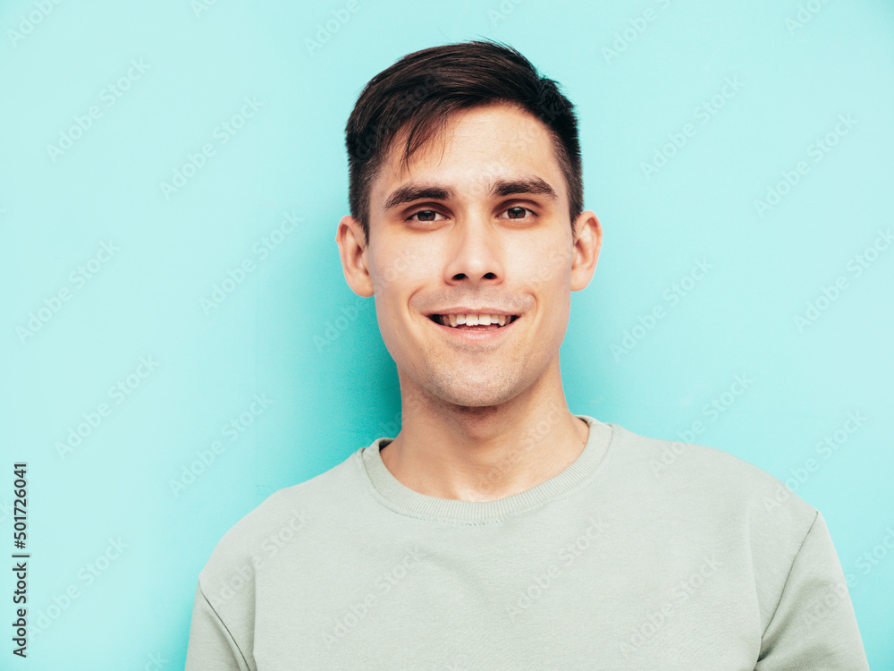 Portrait of handsome smiling stylish hipster lambersexual model.Man dressed in T-shirt and jeans. Fashion male isolated in studio. Posing near blue wall. Cheerful and happy Portrait of handsome smiling stylish hipster lambersexual model.Man dressed in T-shirt and jeans. Fashion male isolated in studio. Posing near blue wall. Cheerful and happy