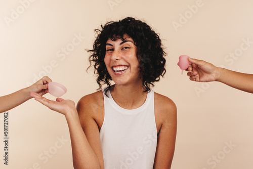 Happy young woman choosing a menstrual disc over a menstrual cup photo