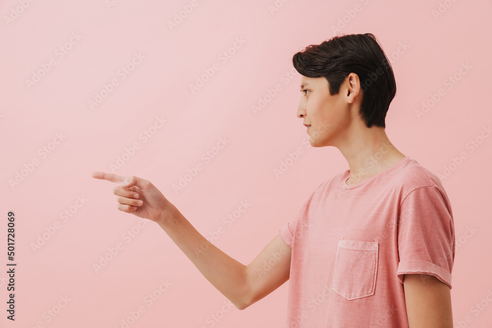 Asian brunette boy with dental brace looking and pointing finger aside Asian brunette boy with dental brace looking and pointing finger aside