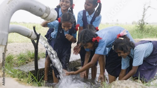 group of village school girl kids playing in water near paddy field - concept of happiness, fun and carefree lifestyle