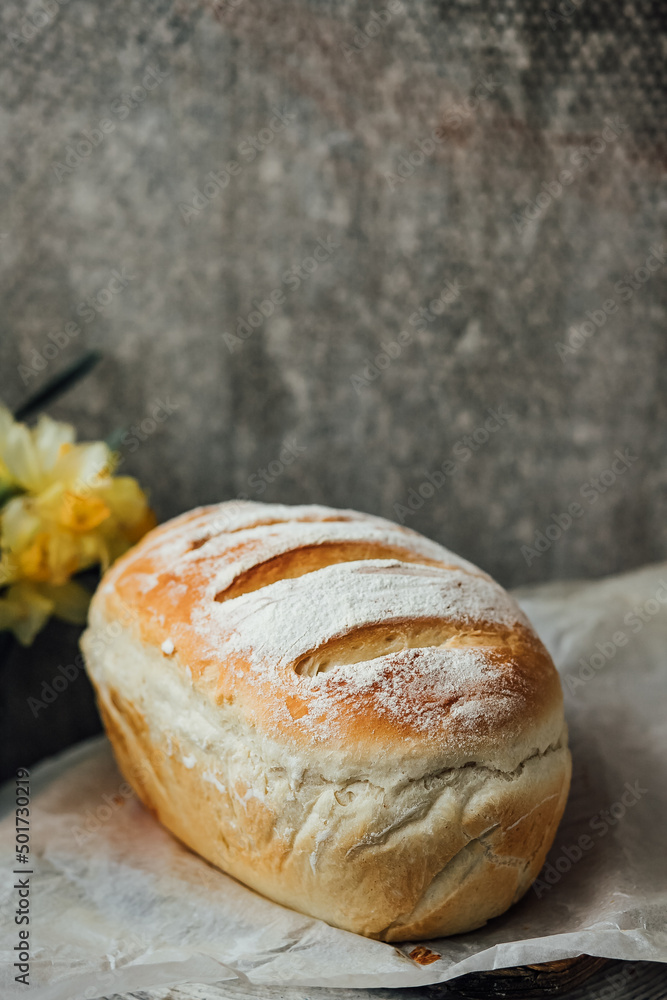 fresh bread only from the oven, cools down on parchment paper, near beautiful flowers