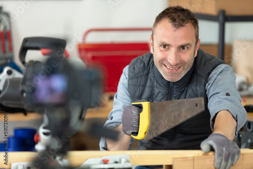 handyman doing a vlog cutting wood with hand saw