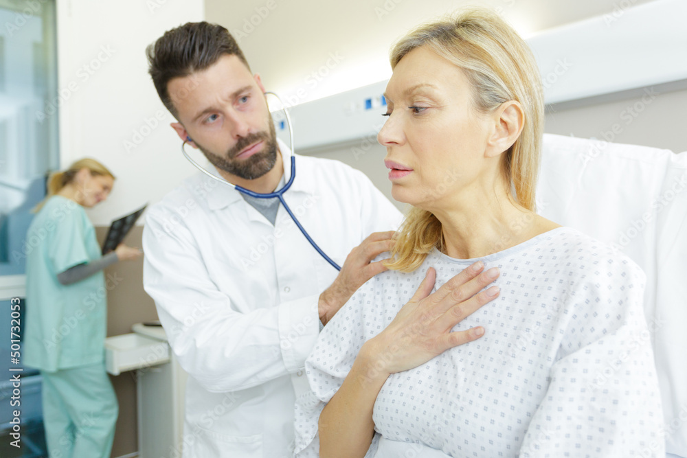 Fototapeta premium doctor using stethoscope to examine anxious woman