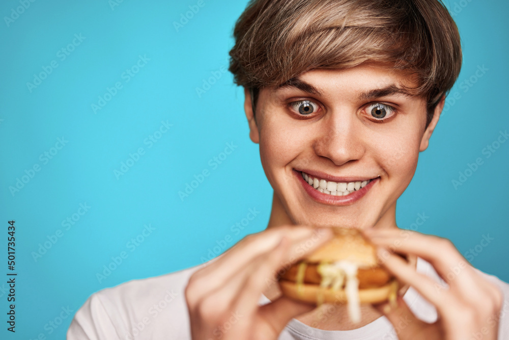 Very hungry young man holding tasty hamburger Very hungry young man holding tasty hamburger