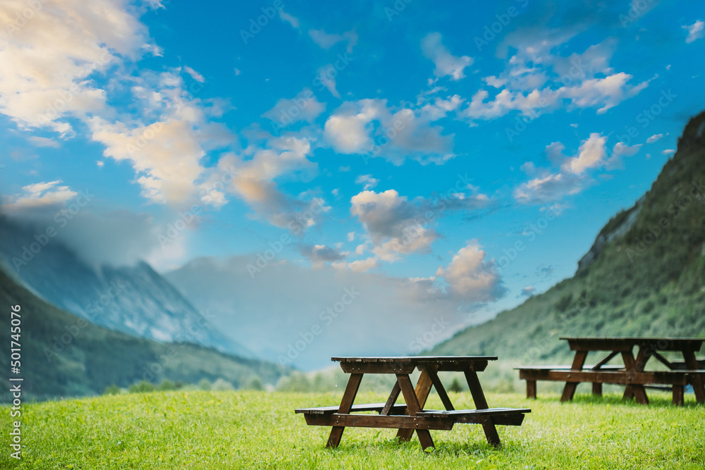 Wooden Tables And Benches In Mountains Summer Landscape. altered calm blue sky above valley.