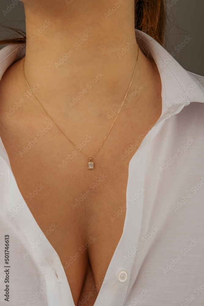 Black and gray A black-haired female model wearing a gray jacket and a white T-shirt jewels a gold necklace around her neck Black and gray A black-haired female model wearing a gray jacket and a white T-shirt jewels a gold necklace around her neck