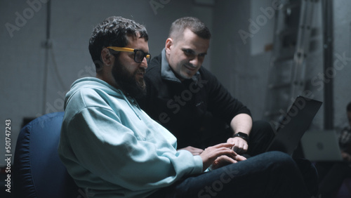 Programmer with laptop and IT director of a company talking and discussing work together in a bomb shelter during the war