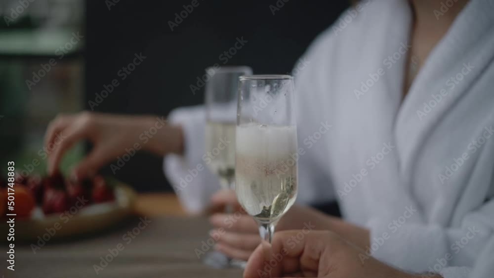 Woman in white robe is throws strawberries in glass with champagne. Perfect breakfast on the weekend holidays. Woman in white robe is throws strawberries in glass with champagne. Perfect breakfast on the weekend holidays.
