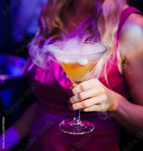 Woman holding a smoky cocktail at a nightclub.