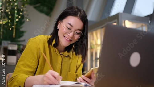 Asian female sitting at workplace looking at laptop screen raising up her index finger feels happy and proud making right creative decision. Self-employed woman came up with great brilliant idea