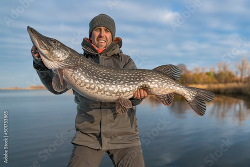 Success pike fishing. Happy fisherman hold huge muskie fish