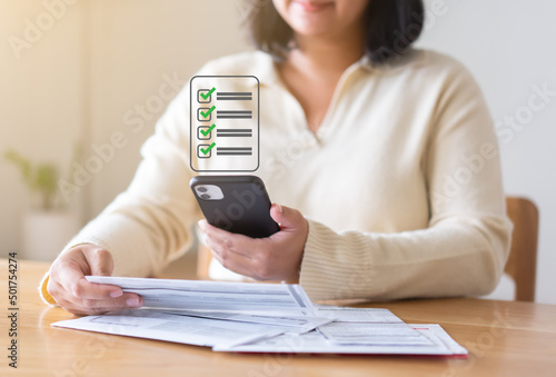 Expenses checklist for payment on the screen of mobile phone. Woman hands holding phone showing list of what have been paid.