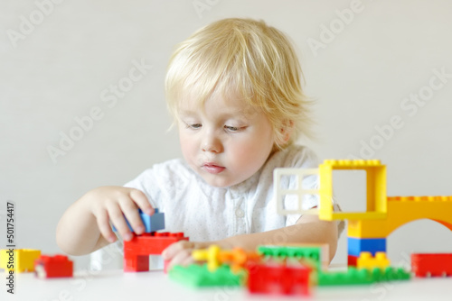 Little child playing with colorful plastic blocks at kindergarten or home. Educational toys for preschooler children. Development through the game.