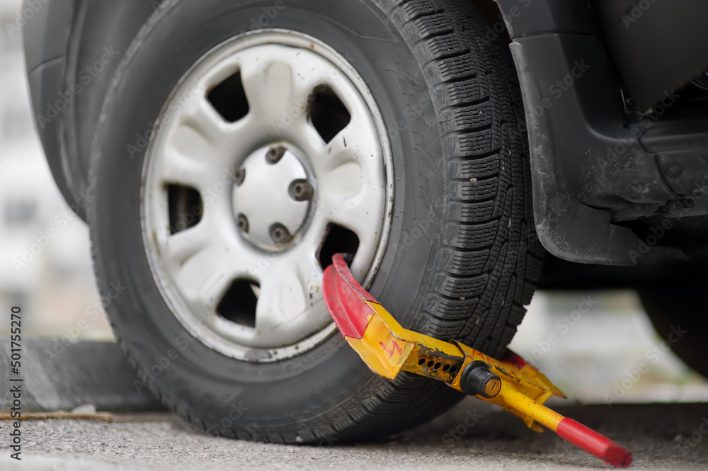 Car wheel blocked by wheel lock. Illegal parking of automobile. Wheel