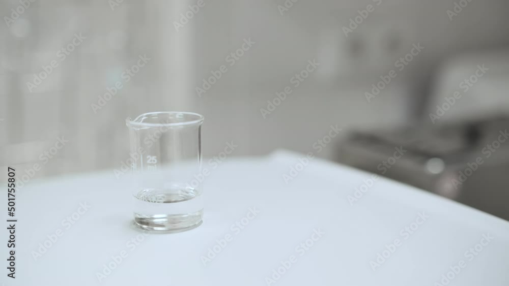 Close up laboratory worker filling the beaker with solvent from the wash bottle. Close up laboratory worker filling the beaker with solvent from the wash bottle.