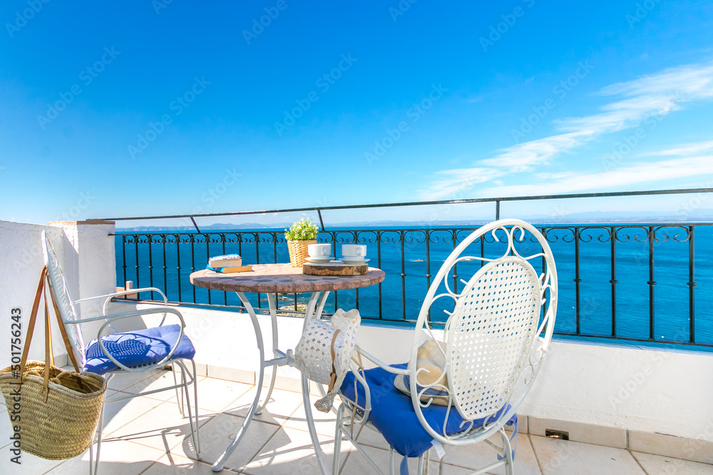 Fototapeta premium white wrought iron table and chairs on a terrace with beautiful views of the sea to enjoy your vacation.