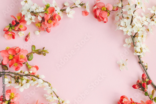 Red flowers and cherry blossom frame layout. Stylish spring flowers composition on pink background flat lay. Floral greeting card template with space for text. Happy Mothers day and Womens day