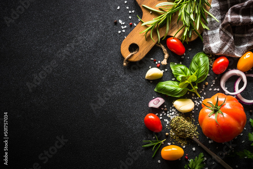 Food cooking background on black stone table. Fresh vegetables  herbs and spices. Ingredients for cooking with copy space.