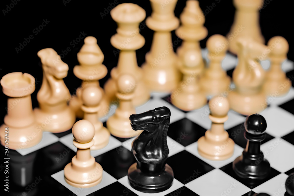Close up of Chess pieces on a reflective mirror board surface with black background Close up of Chess pieces on a reflective mirror board surface with black background