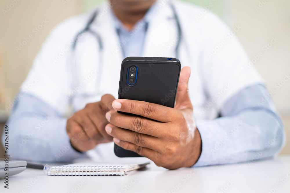 close up shot of doctor using mobile phone while at hospital - concept of virutal doctor consultation , taking break and healthcare service. close up shot of doctor using mobile phone while at hospital - concept of virutal doctor consultation , taking break and healthcare service.