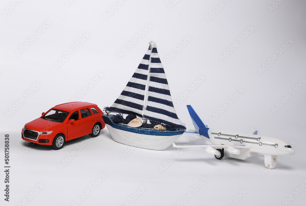 Small model car with passenger plane and sailboat isolated on white background. Travel concept, transport