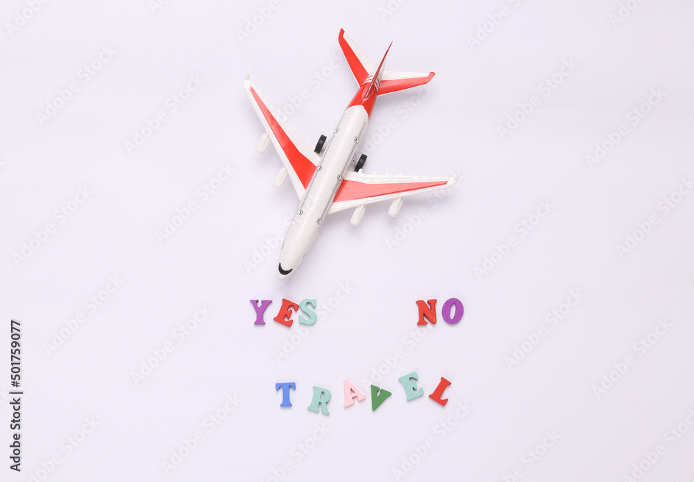 Travel yes or no. Miniature airplane on white background. Travel concept, flat lay