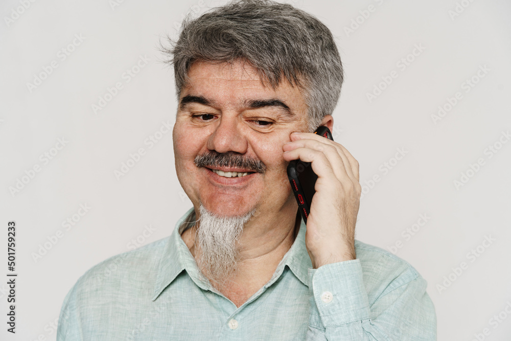 Senior grey man with mustache and beard talking on cellphone Senior grey man with mustache and beard talking on cellphone