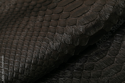 dark brown dyed genuine natural python leather on the wooden table	