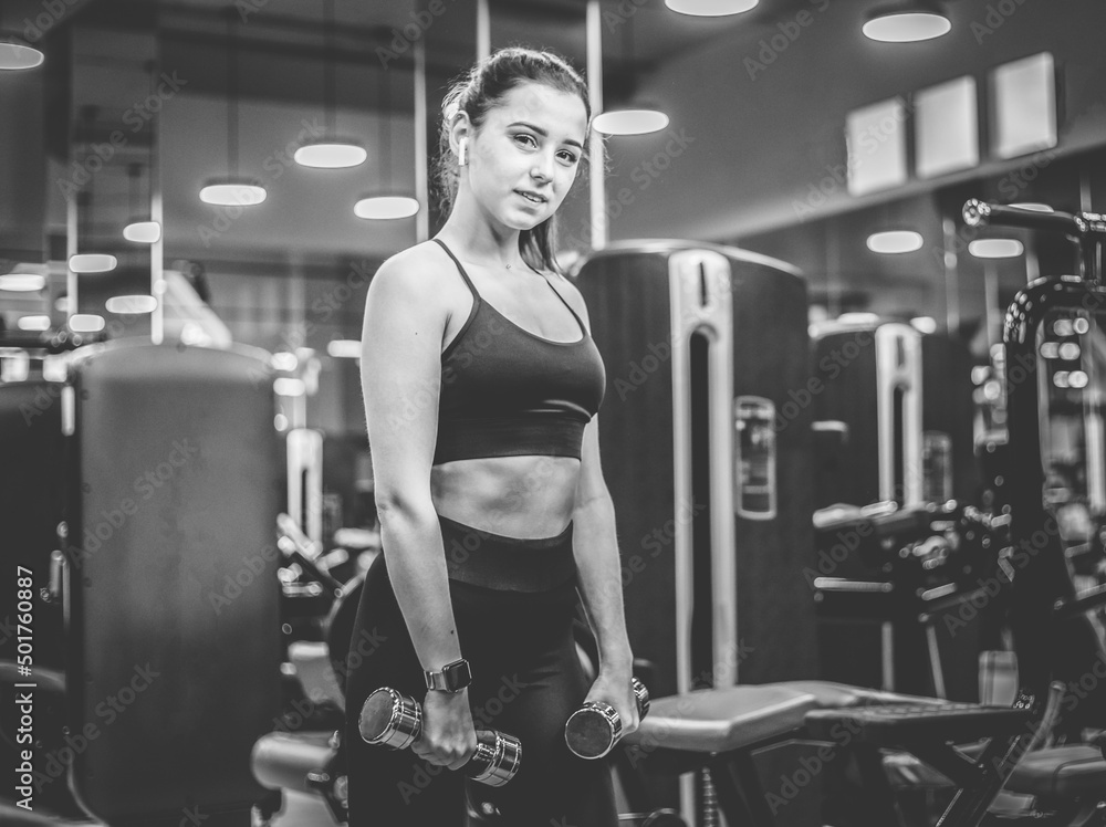 Fit woman holding light dumbbells in modern gym Fit woman holding light dumbbells in modern gym